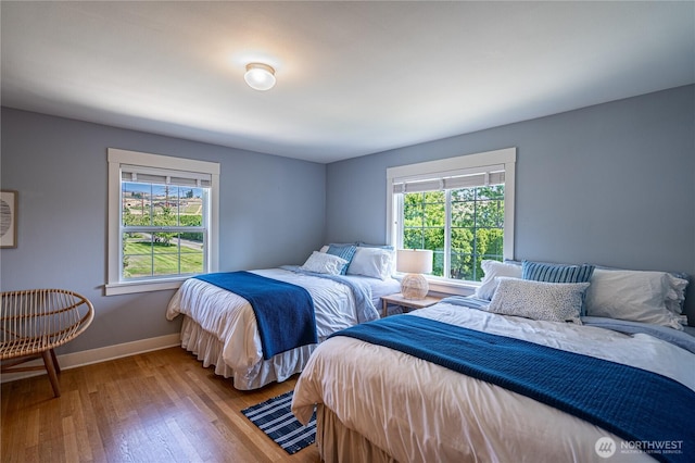 bedroom with multiple windows, baseboards, and wood-type flooring