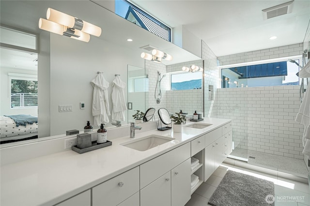 bathroom featuring a sink, connected bathroom, double vanity, and a tile shower