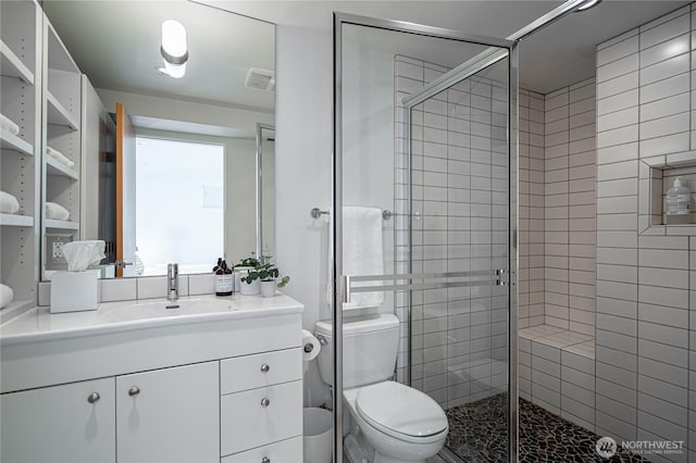 bathroom with visible vents, a stall shower, toilet, and vanity