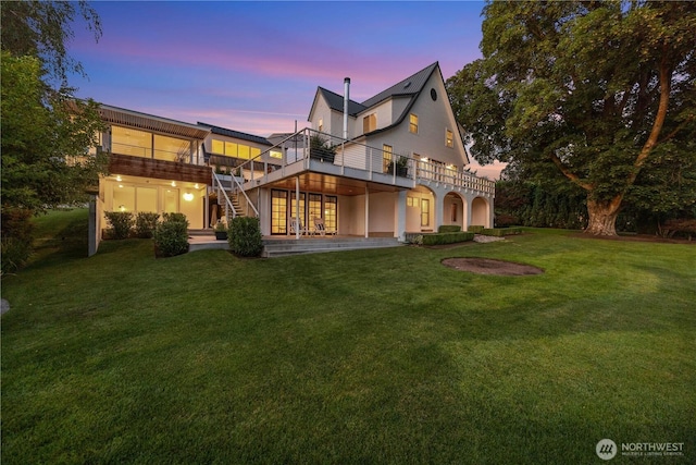 back of property with a yard, a wooden deck, and stairs