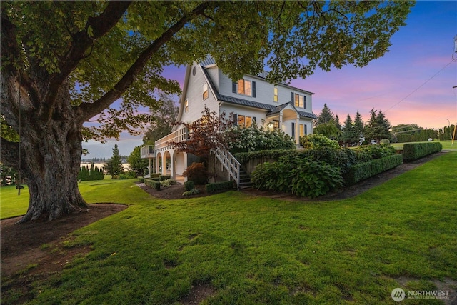 exterior space with stairway, metal roof, and a front lawn