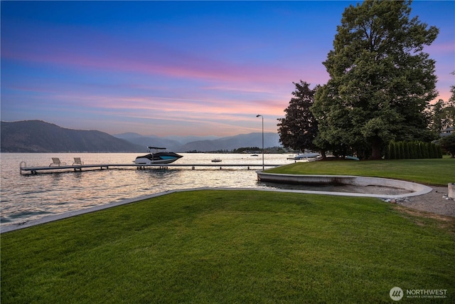 yard at dusk featuring a water and mountain view