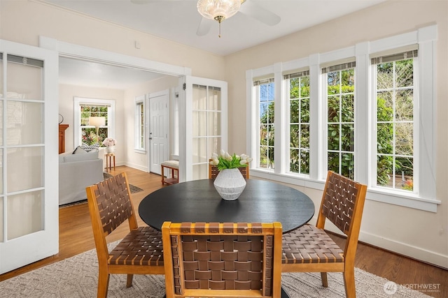 dining space with ceiling fan, baseboards, and wood finished floors