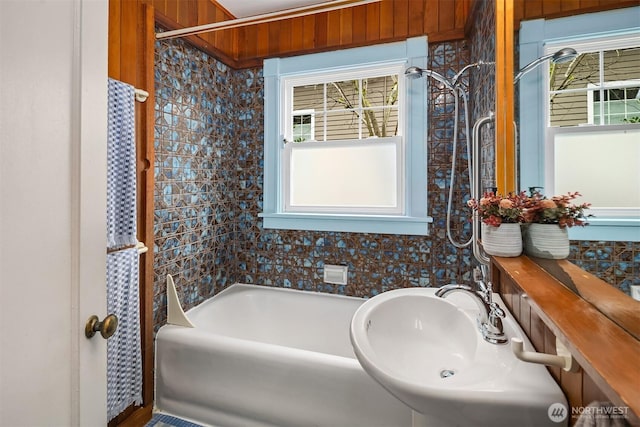 bathroom featuring a bathing tub, walk in shower, and a sink