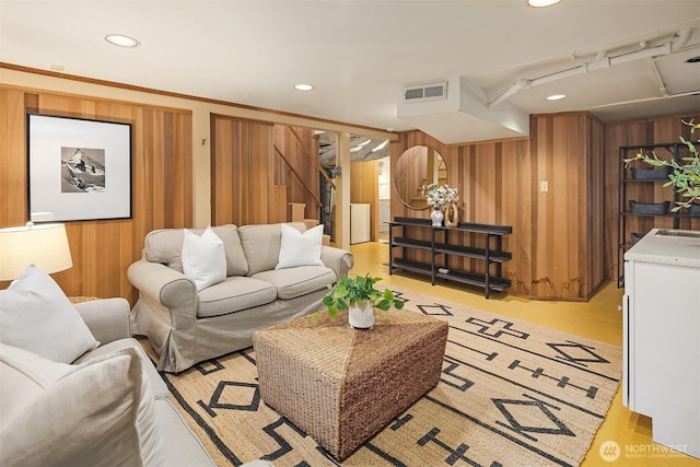 living room featuring recessed lighting, visible vents, wood walls, and stairs