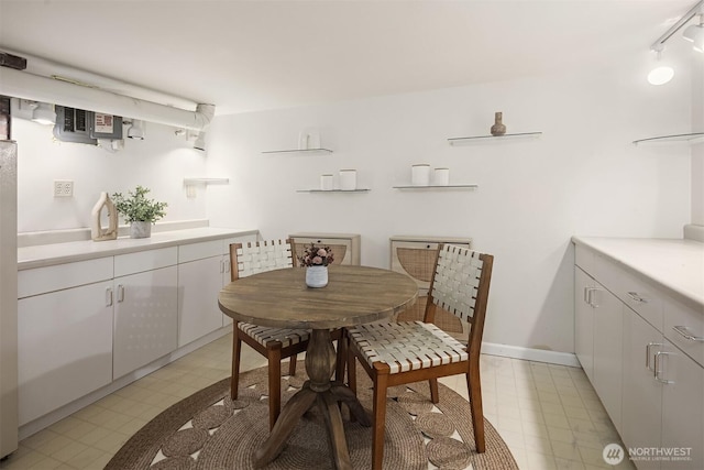 dining space with baseboards, light floors, and rail lighting