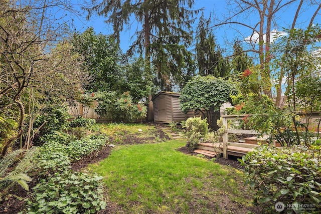 view of yard featuring a garden, a storage unit, an outdoor structure, and fence