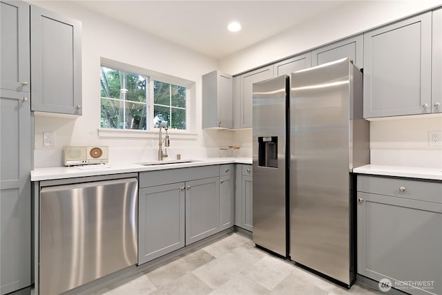 kitchen with stainless steel appliances, recessed lighting, light countertops, gray cabinetry, and a sink