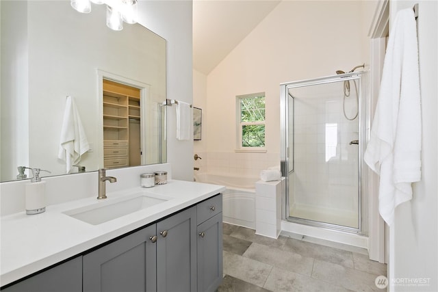 bathroom featuring a stall shower, lofted ceiling, a spacious closet, vanity, and a bath