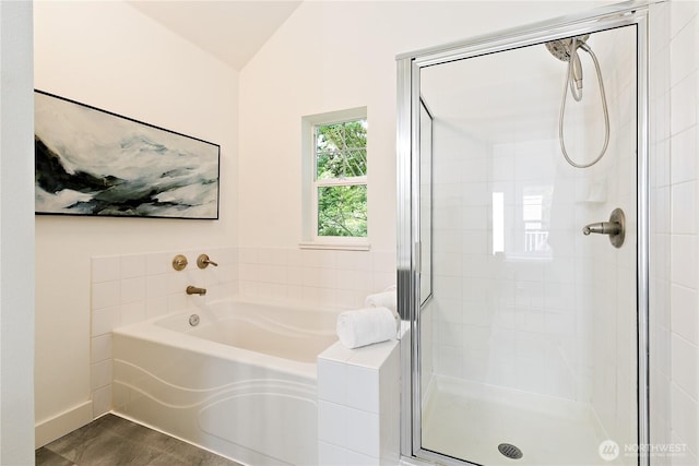 full bathroom featuring lofted ceiling, a shower stall, and a bath