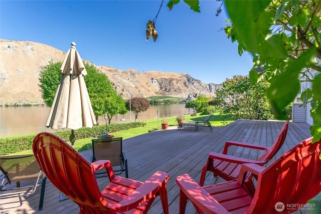 wooden deck featuring a lawn and a water and mountain view