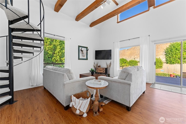 living room with wood finished floors, beamed ceiling, a towering ceiling, and stairs