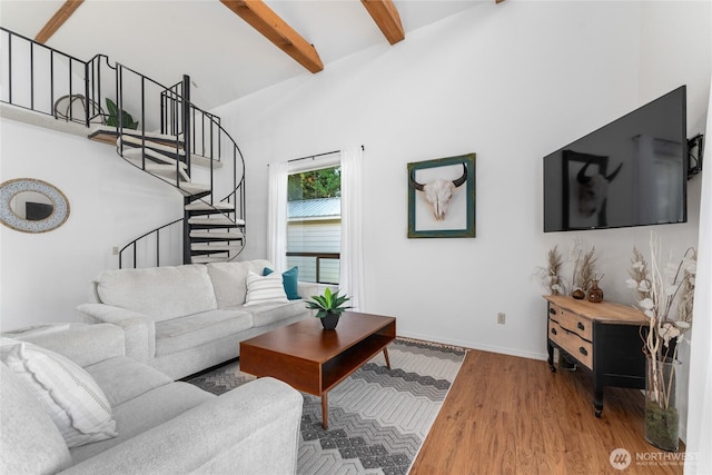 living room featuring stairs, baseboards, beamed ceiling, and wood finished floors