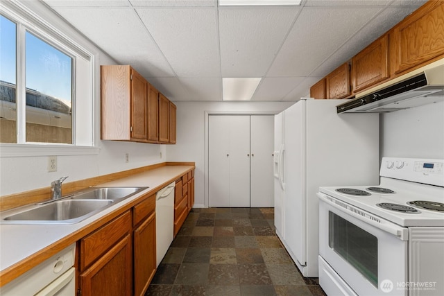 kitchen with a paneled ceiling, stone finish flooring, a sink, white appliances, and under cabinet range hood