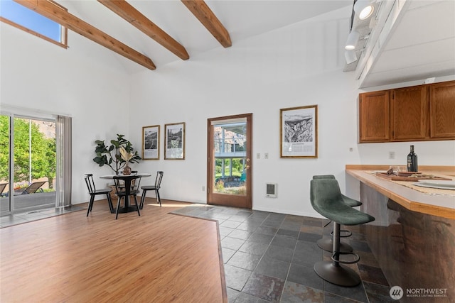 interior space featuring dark wood-style floors, beamed ceiling, a towering ceiling, and baseboards