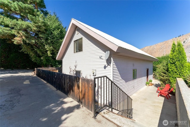 view of side of home with a patio area, fence, and a mountain view