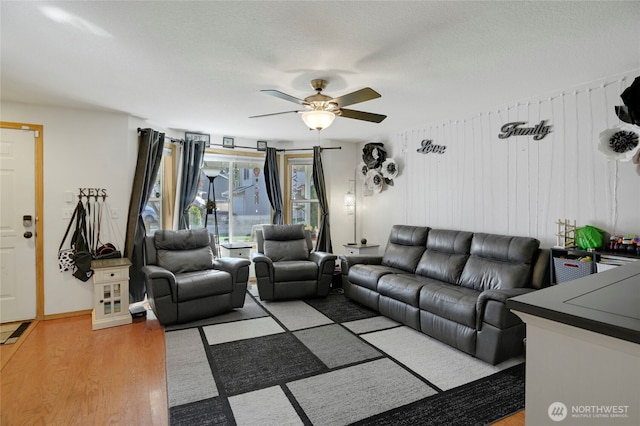 living room with light wood-style flooring, ceiling fan, and a textured ceiling