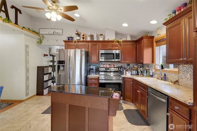 kitchen with a center island, backsplash, appliances with stainless steel finishes, vaulted ceiling, and a sink