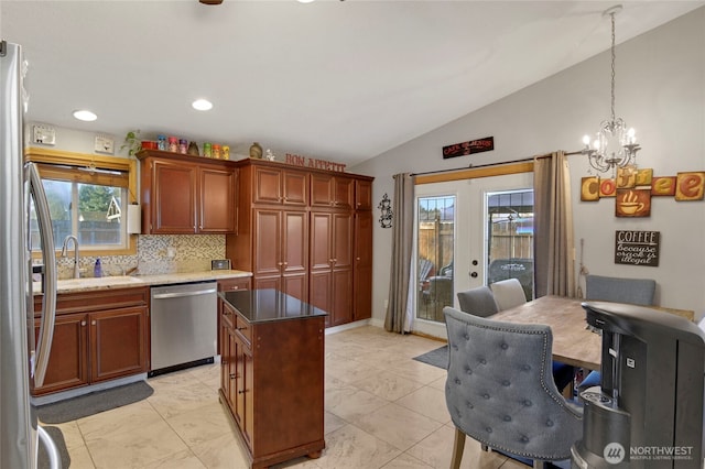 kitchen with stainless steel appliances, a sink, vaulted ceiling, french doors, and backsplash