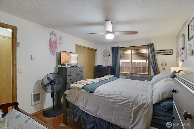 bedroom featuring a textured ceiling, wood finished floors, a ceiling fan, baseboards, and a closet