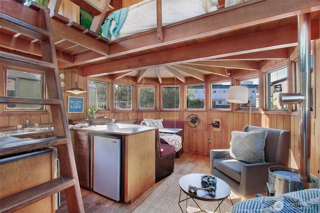 interior space featuring wooden walls, beam ceiling, light wood-style flooring, and refrigerator