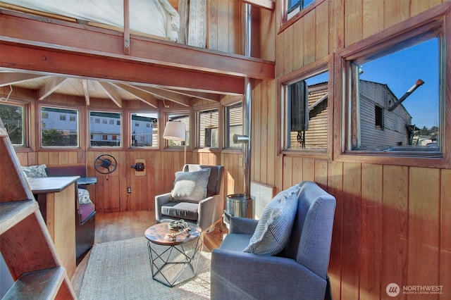 interior space featuring beam ceiling, wooden walls, and wood finished floors