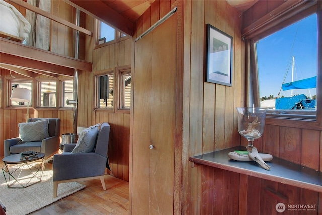 living area with plenty of natural light, wooden walls, and wood finished floors