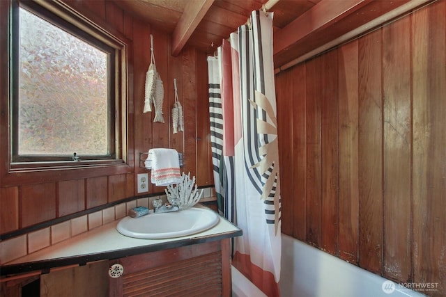 bathroom with shower / tub combo with curtain, vanity, and wooden walls