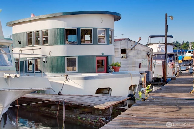 rear view of property with a water view, boat lift, and stucco siding