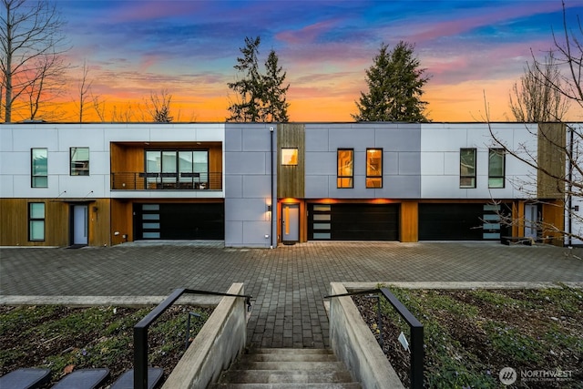 modern home with a balcony, decorative driveway, and a garage