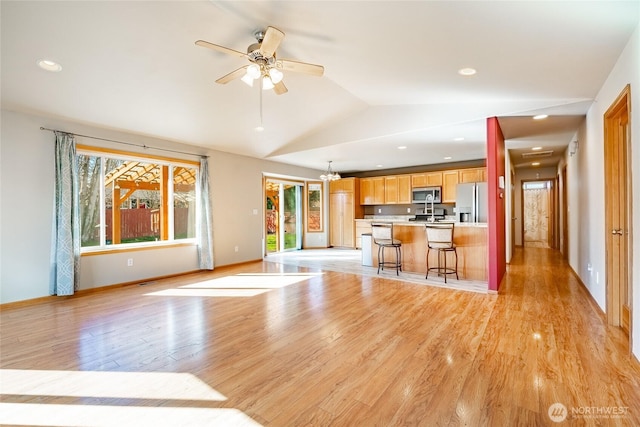 interior space with lofted ceiling, light wood-style flooring, stainless steel appliances, light countertops, and open floor plan