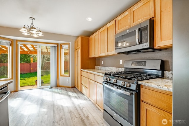 kitchen with light wood-type flooring, a notable chandelier, appliances with stainless steel finishes, and light brown cabinetry