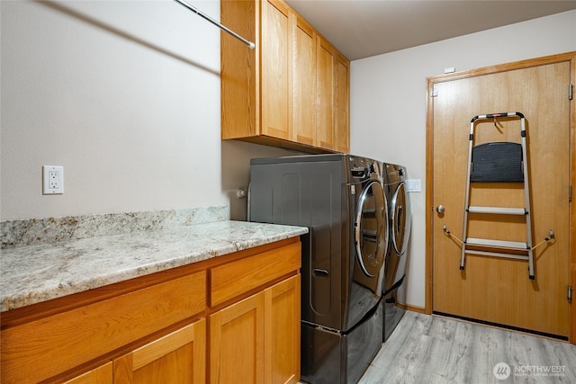 laundry room featuring light wood-style flooring, cabinet space, and independent washer and dryer