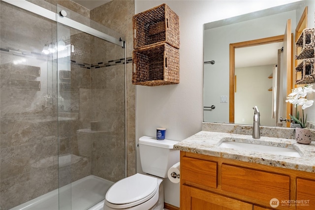 full bathroom featuring a shower stall, toilet, and vanity