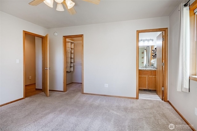 unfurnished bedroom featuring a walk in closet, baseboards, and light colored carpet