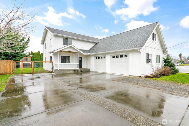 modern farmhouse with fence, board and batten siding, concrete driveway, an attached garage, and a shingled roof