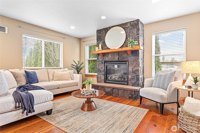 living room with wood finished floors, recessed lighting, a fireplace, and a healthy amount of sunlight