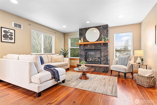 living area featuring recessed lighting, visible vents, wood finished floors, and a fireplace