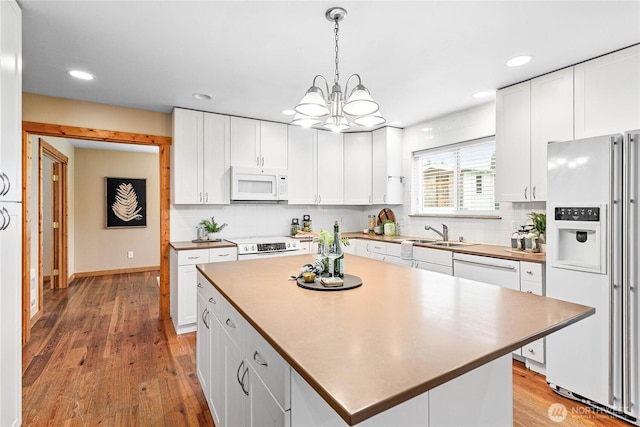 kitchen with white cabinetry, white appliances, light wood-style flooring, and backsplash