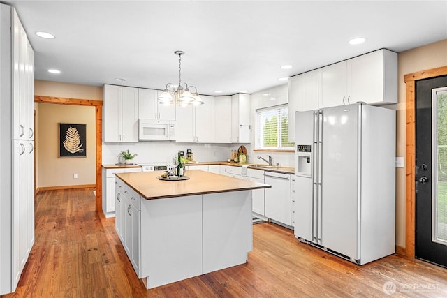 kitchen featuring white appliances, a kitchen island, recessed lighting, white cabinets, and light wood-style floors