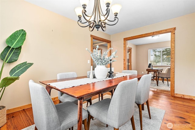 dining area with an inviting chandelier, light wood-style floors, and baseboards