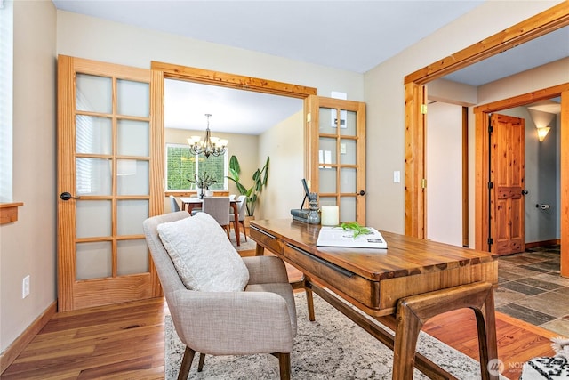 office space with baseboards, an inviting chandelier, and wood finished floors