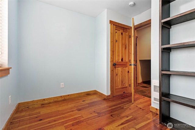 unfurnished bedroom featuring wood finished floors and baseboards