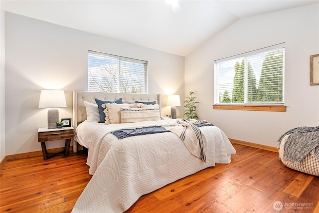 bedroom with hardwood / wood-style flooring, multiple windows, baseboards, and vaulted ceiling