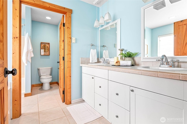 bathroom featuring tile patterned floors, toilet, double vanity, and a sink