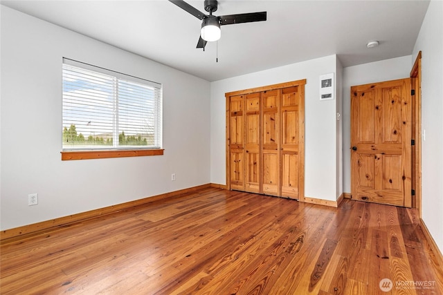 unfurnished bedroom featuring ceiling fan, a closet, baseboards, and light wood-style flooring