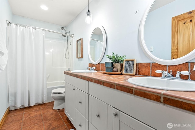 full bathroom with double vanity, tile patterned floors, toilet, and a sink