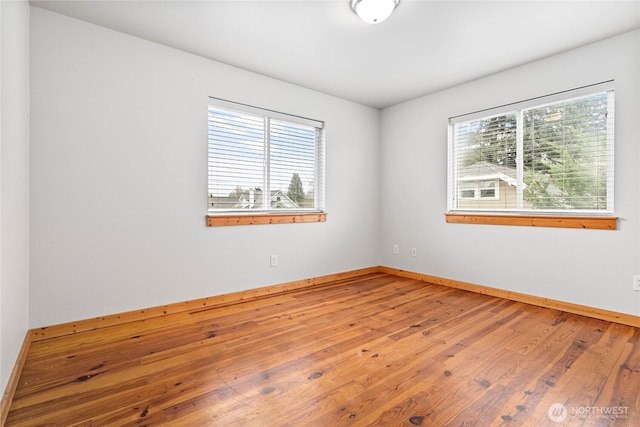 unfurnished room with baseboards and hardwood / wood-style flooring