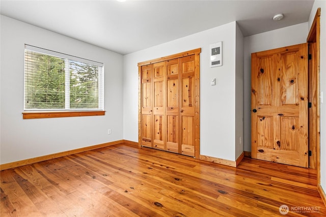 unfurnished bedroom featuring a closet, baseboards, and light wood-style floors