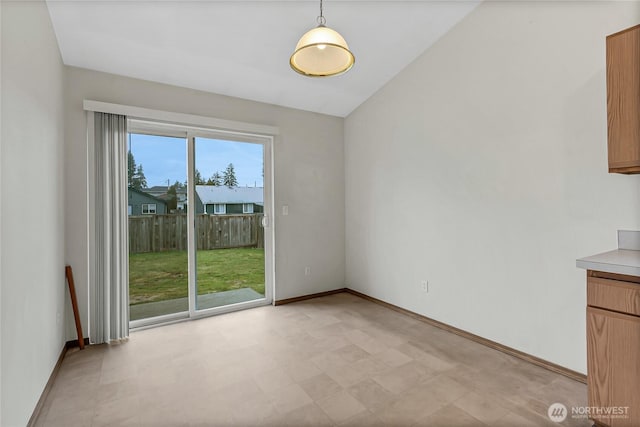 unfurnished dining area with vaulted ceiling and baseboards